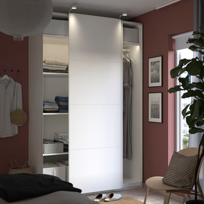 Moderne slaapkamer met witte PAX kledingkast, gespiegelde en massieve deuren, kleding en kunst.