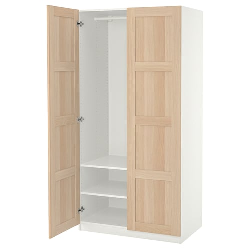 Een open ikea PAX kledingkast. Het is lichtbeige met houten panelen, een wit interieur en twee verstelbare planken.