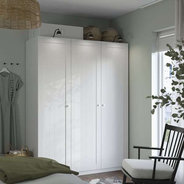 Witte kledingkast, zwarte stoel, groen bed, rieten mand, decor.