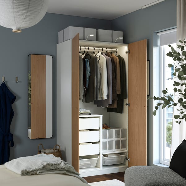 Open kledingkast met kleding, planken en opbergdozen in een slaapkamer.