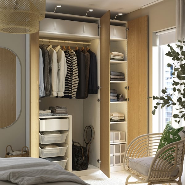 Open kledingkast met kleding, planken met opgevouwen items en opbergbakken. Geïntegreerde verlichting verlicht het interieur.