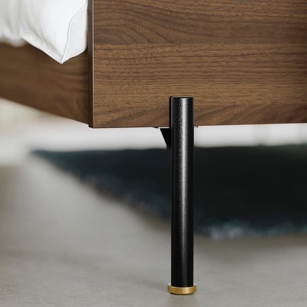 Modern bed met strakke walnoothouten afwerking en sterke zwarte metalen poten. Hoogwaardig ontwerp, stevige constructie.