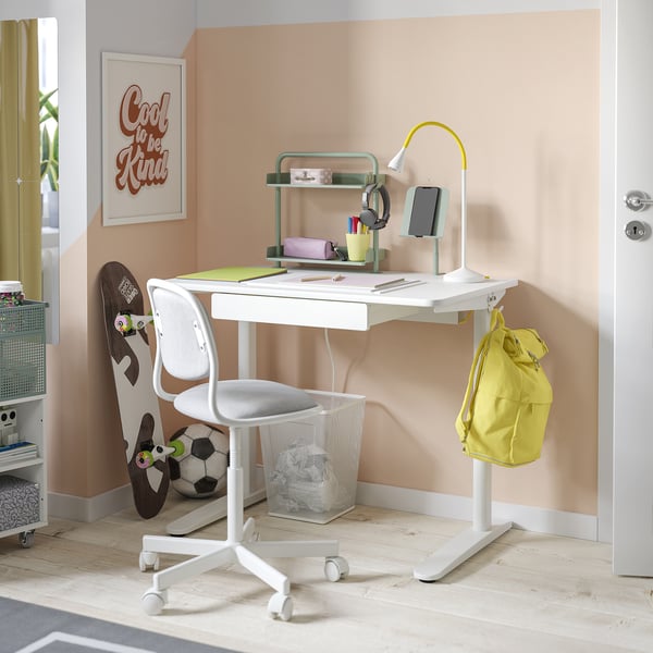 Klein wit bureau met lade, heldere lamp, stoel, sportuitrusting, gele rugzak.