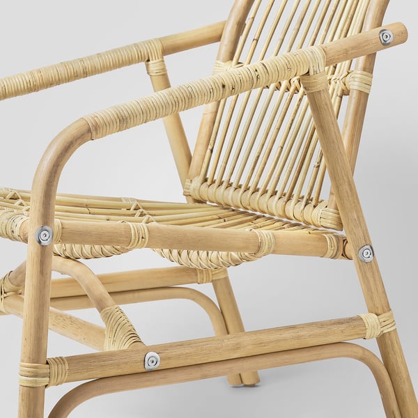 Geweven rotan fauteuil, handgemaakt, vanaf de zijkant met de nadruk op natuurlijk, duurzaam materiaal en comfortabel, gebogen ontwerp.