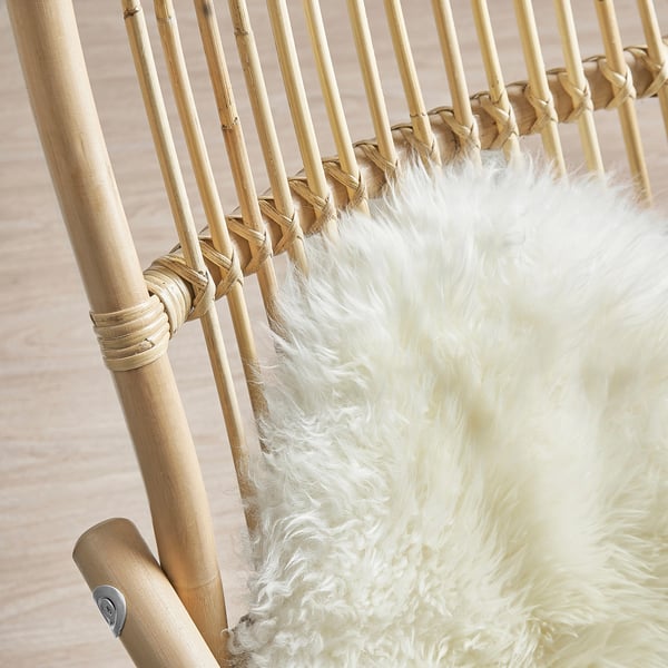 Afbeelding toont een handgeweven rotan fauteuil met een donzig wit kussen, dat een natuurlijk, stevig ontwerp benadrukt.
