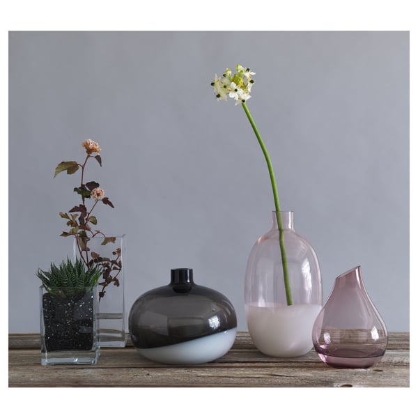 SANNOLIK vazen in zwart, roze en helder glas. Op een houten ondergrond worden verschillende vormen en maten weergegeven.