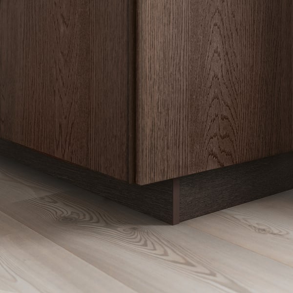 Donkerhouten kast met zichtbare nerf, massief eiken rand op de basis, staat op een lichte houten vloer en toont SINARP fronten elegantie en detail.