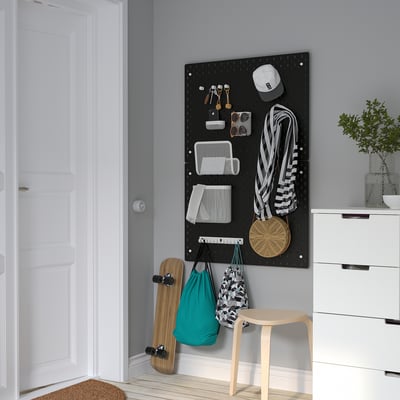 Het zwarte ophangbord van SKÅDIS organiseert accessoires in de buurt van witte deuren en lades. Geschikt voor tassen, sleutels en skateboard.