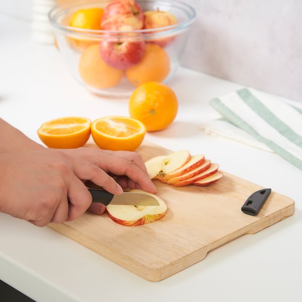 Persoon die appel met mes op snijraad, fruit op achtergrond snijdt