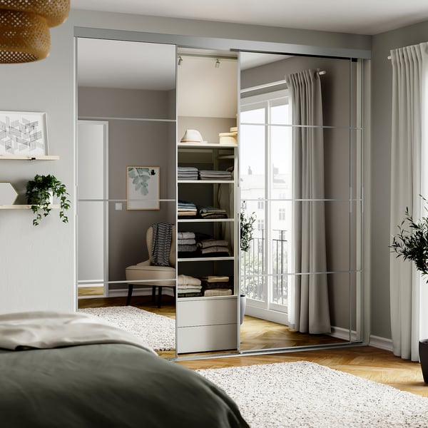 Moderne slaapkamer met gespiegelde kastdeuren, groen hoofdeinde bed en grote ramen met grijze gordijnen.