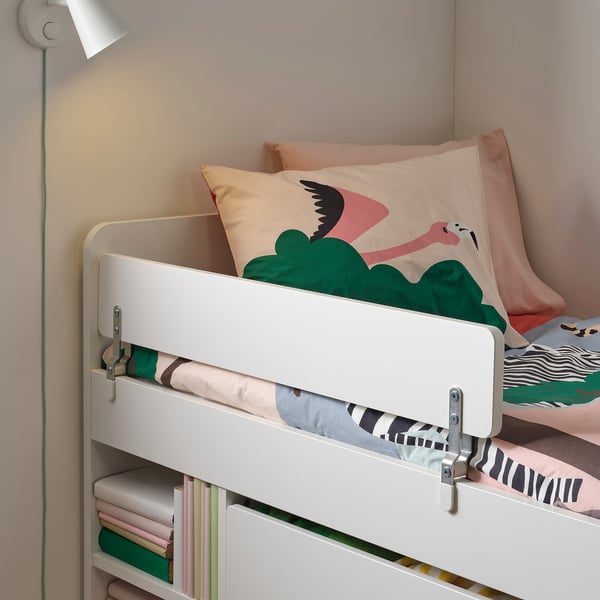 Witte kinderbedden met veiligheidsleuning, kleurrijk beddengoed en een aan de muur gemonteerde lamp.