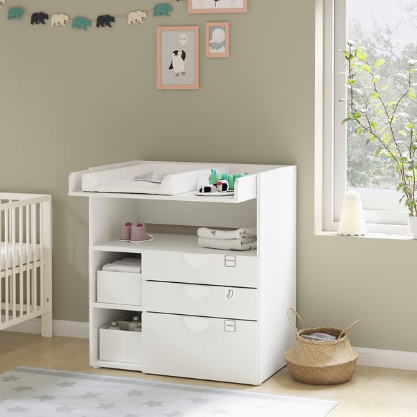 Modern wit verschoonstation voor baby's met lades en planken, onderdeel van een kinderkameropstelling.
