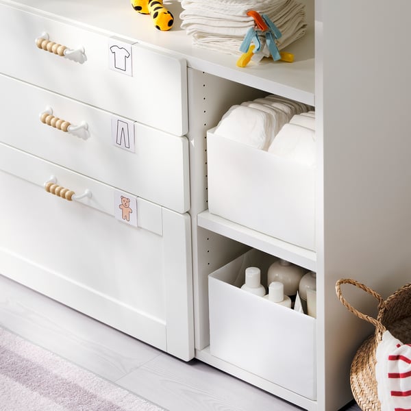 Witte babyverschoontafel met opbergruimte, houten handvatten en luiers.