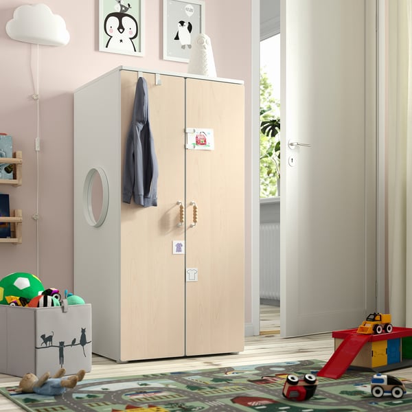 Houten kinderkledingkast met spiegel, soft-close deuren, speelgoedkist en speelmat. Roze muren met decor en verbindingsdeur.