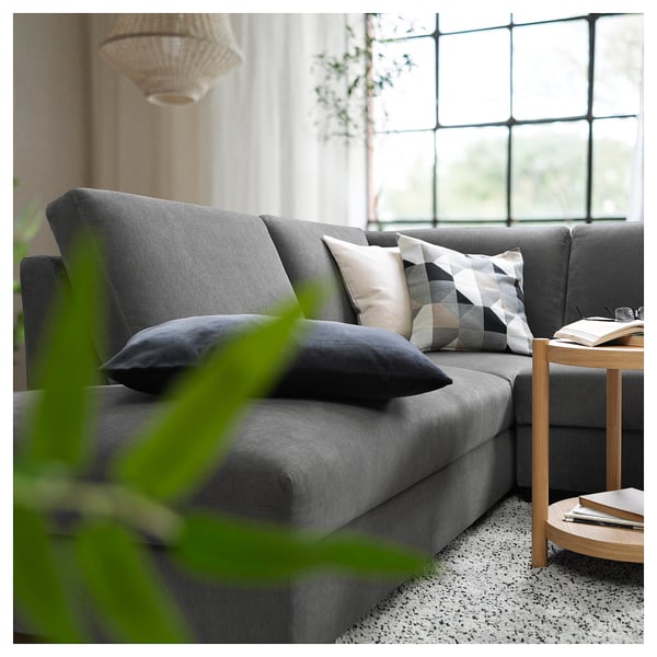 Een moderne woonkamer met een grijze SÖRVALLEN bank. Het heeft kleurrijke kussens en een houten bijzettafel.