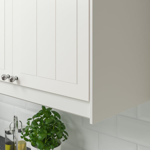 Witte keukenkast met zilveren handgrepen en onderkastverlichting, met een groene plant en oliedispensers op het aanrecht.