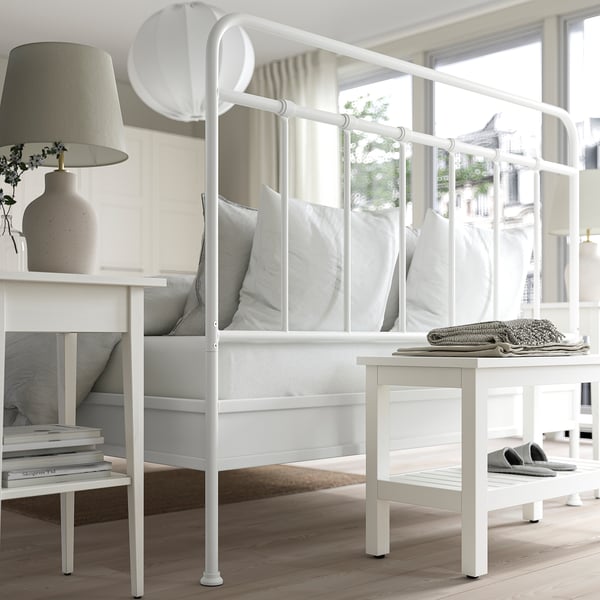 Modern wit metalen bed met gebogen hoofdeinde, schoon ontwerp, door raam.