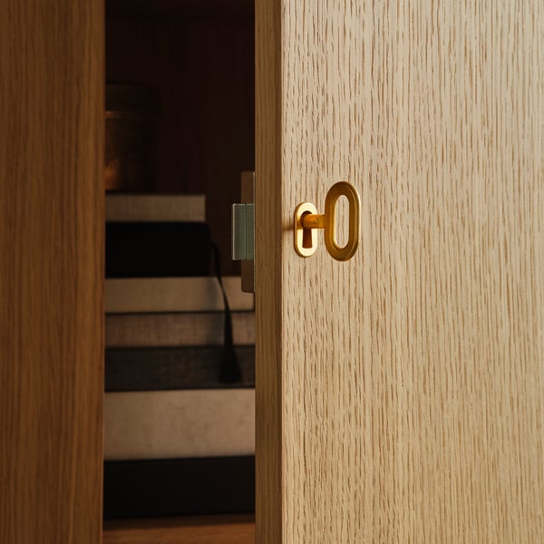 Close-up van een lichthouten kast met een goudkleurig slot en sleutel, met hoogwaardige afwerking en strak design.