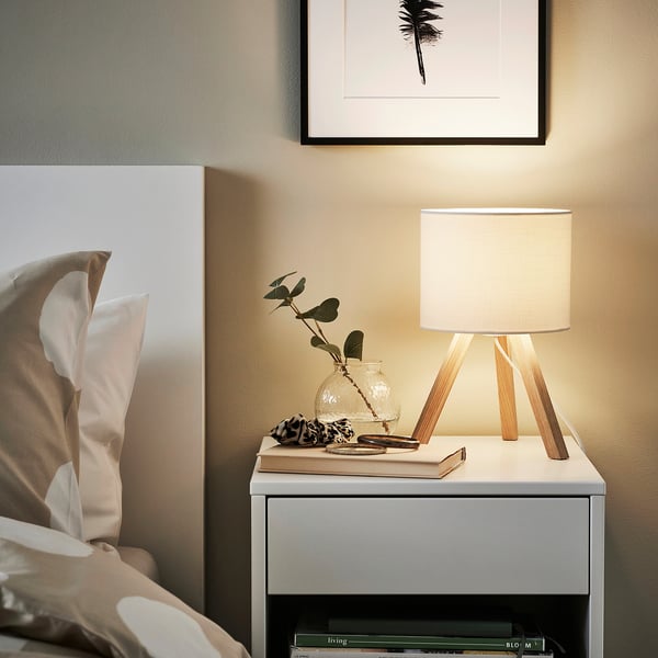 Gezellig nachtkastje: STORSEGEL lamp, boeken, plant, palmblad kunst.