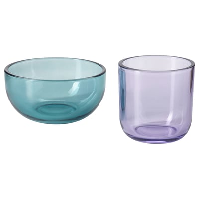 Twee glazen voorwerpen, een komvormig in groenblauw en een komvormig in lavendel, naast elkaar tentoongesteld.