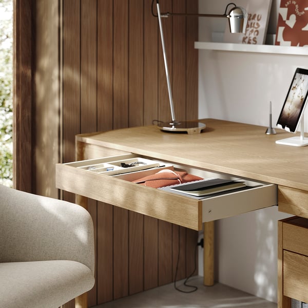 Houten bureau met open lade, benodigdheden, lamp, tablet, stoel.