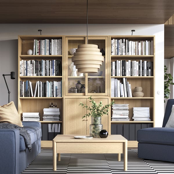 Woonkamer met TONSTAD planken, boeken en decor. Blauwe en grijze meubels, salontafel met dienblad en plant.