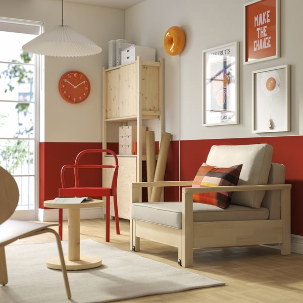 Gezellige woonkamer met TORNSBORG fauteuil, rode stoel, galerijwand en groot raam.