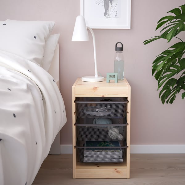 Houten TROFAST opberger bij bed met lamp, fles & planten.