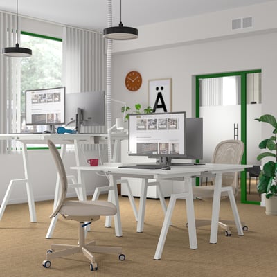 Modern kantoor met TROTTEN zit-/sta-bureaus. Digitale schermen, stoelen, minimalistische inrichting, ruim en georganiseerd.