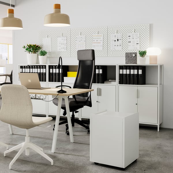 Modern kantoor met TROTTEN witte opbergkast met zwarte mesh stoel en licht houten bureau. Georganiseerd met bindmiddelen, planten en hanglampen.