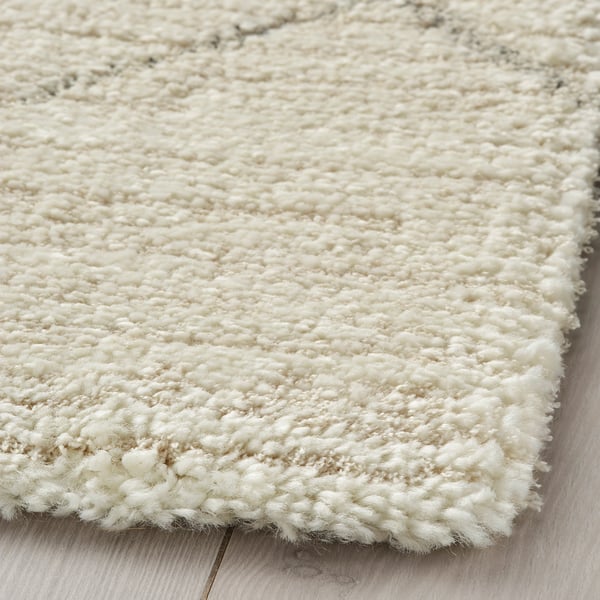 Close-up van TVERSTED tapijt hoek, dichte, zachte textuur, neutrale kleur, pluche materiaal.