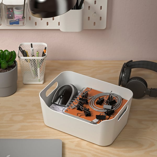 Houten bureau met georganiseerde kantoorbenodigdheden. In de witte bak passen kleine voorwerpen zoals clips en snoeren. Ook een koptelefoon en een dichtgeklapte laptop zijn aanwezig.