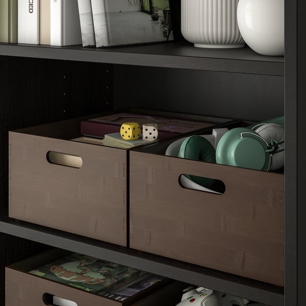 Kast met donker gebeitste bamboe dozen, opbergspullen, spelaccessoires en een decoratieve vaas.