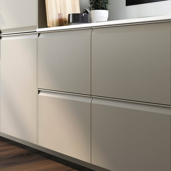 Moderne keuken met matbeige UPPLÖV-kasten, strakke handgrepen en subtiele afgeschuinde randen, aangevuld met een kleine potplant op het aanrecht.