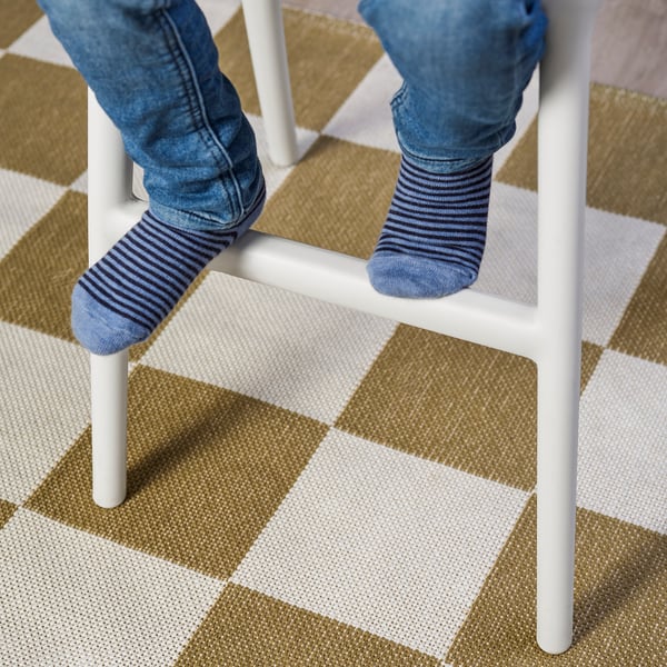 Kindervoeten in gestreepte sokken op een witte junior stoel, perfect voor eettafelhoogte.