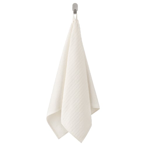 Een VÅGSJÖN witte handdoek hangend aan een haak. Het rechthoekige, gemaakt van 100% katoen, met een gestructureerd oppervlak.