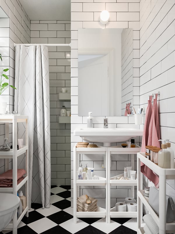 Moderne badkamer met witte VESKEN planken met diverse toiletartikelen, grijs betegelde wanden en een zwart-wit geblokte vloer.