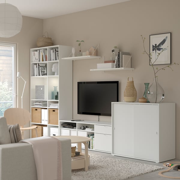 Moderne woonkamer met witte VIHALS opbergmeubels, tv, beige bank en decoratieve items.