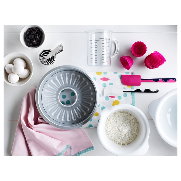 Bakscène met VISPAD grijze kom, roze spatel, ingrediënten, meetgereedschap op gestippelde doek.