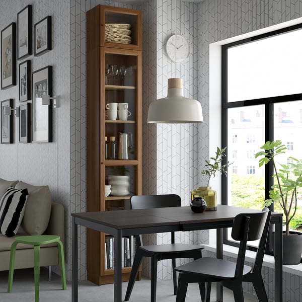 Dining area with BILLY bookcase, table, lamp, sofa, plant, city view.