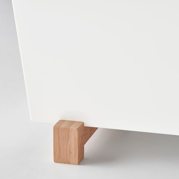 A stylish plant stand with wooden feet supporting a sleek, white surface, highlighting quality materials and design.
