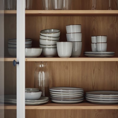 Stoneware bowls, cups, and plates on wooden shelves.