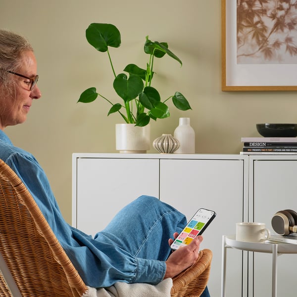 Person using smartphone with apps, plant, books, mug.