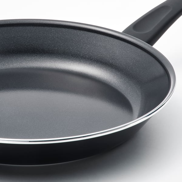 Black non-stick frying pan with dark handle on white surface, showing quality cooking surface.