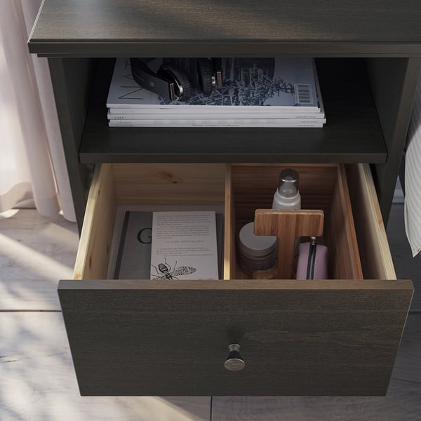 Wooden bedside table drawer with personal items, books, and organisers.