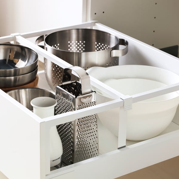Open kitchen drawer showing pots, bowls, and graters inside. Drawer has multiple compartments for organised storage.