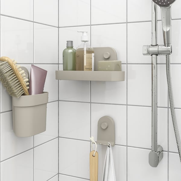 Beige suction-cup organiser in shower. Holds bottles, brush, and towels on tiled wall.
