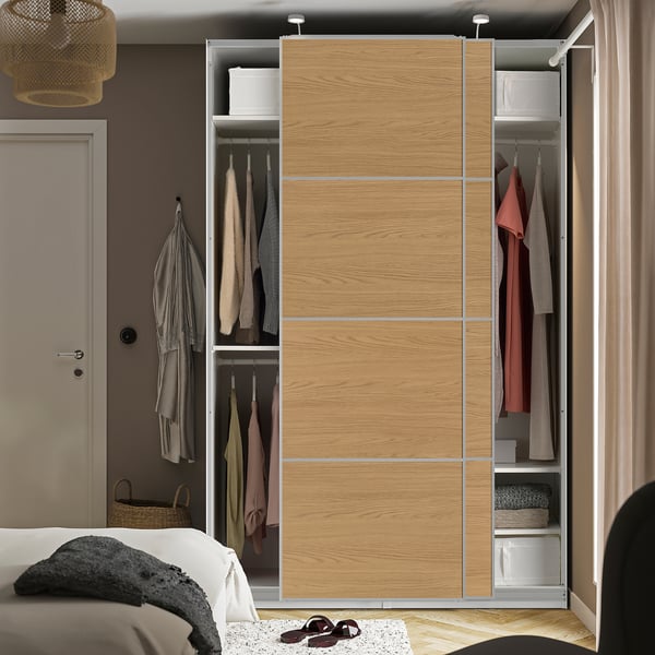 Bedside closet with sliding doors and hanging clothes.