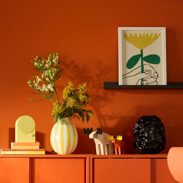 Orange shelf with RÖDALM frame, striped vase, colourful decor.