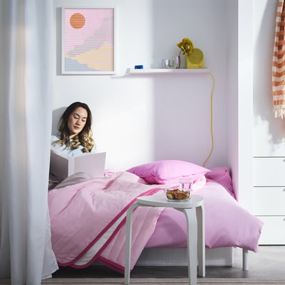 Person on pink laptop in minimal room.